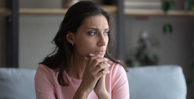 Middle-aged woman sitting on sofa staring out the window