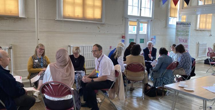 People meeting in a hall sitting in groups having discussions 