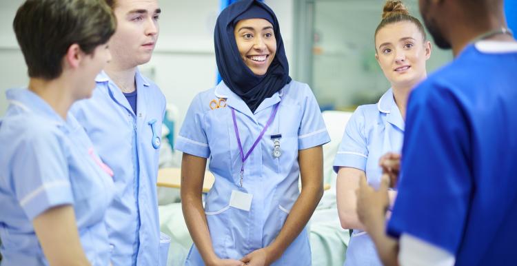 Group of nurses and doctors of various nationalities talking in a hospital ward