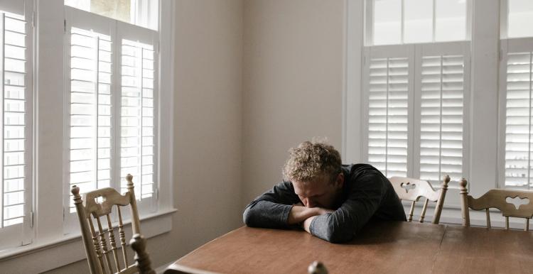 A man alone and isolated, sat at a table.