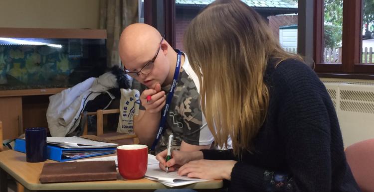 Alice sitting at a desk working with one of our volunteers