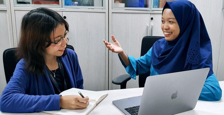 Two people sat at a computer talking