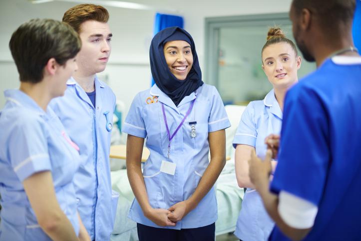 Group of nurses and doctors of various nationalities talking in a hospital ward