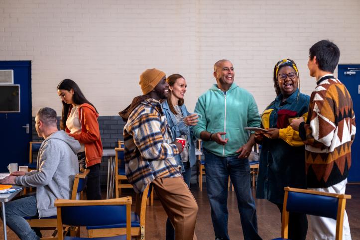 Diverse group of people standing and talking in a community hall