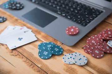 Laptop with playing cards and poker chips scattered on top