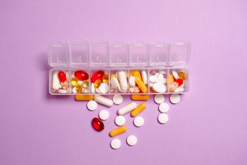 Various tablets and medications spilling out of a clear plastic pill organiser