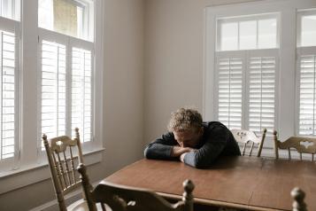 A man alone and isolated, sat at a table. 