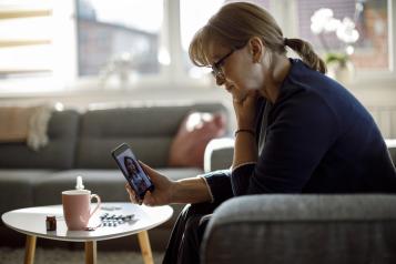 Middle-aged lady with glasses in her home, on a video call with a doctor.