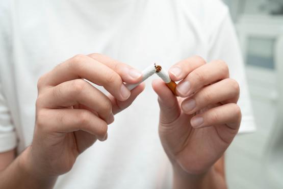 Person in white t-shirt breaking a cigarette in half