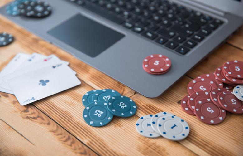 Laptop with playing cards and poker chips scattered on top