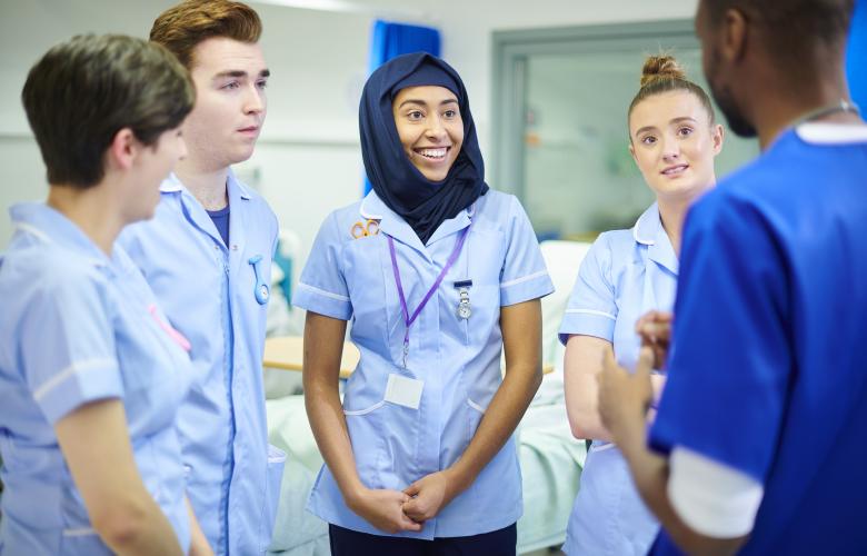 Group of nurses and doctors of various nationalities talking in a hospital ward